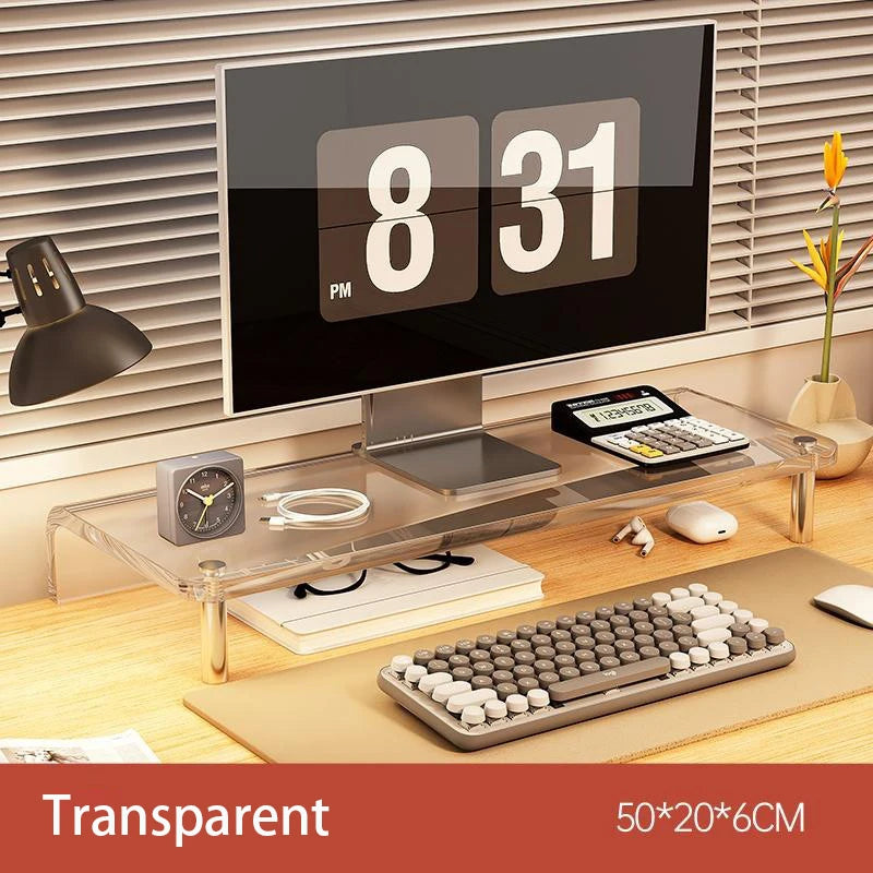 A desktop monitor stand with clear acrylic legs and a transparent top shelf, shown holding a computer monitor, keyboard, mouse, and other desk accessories in a home office setting. Text at the bottom reads 'Transparent' and '50*20*6CM'.