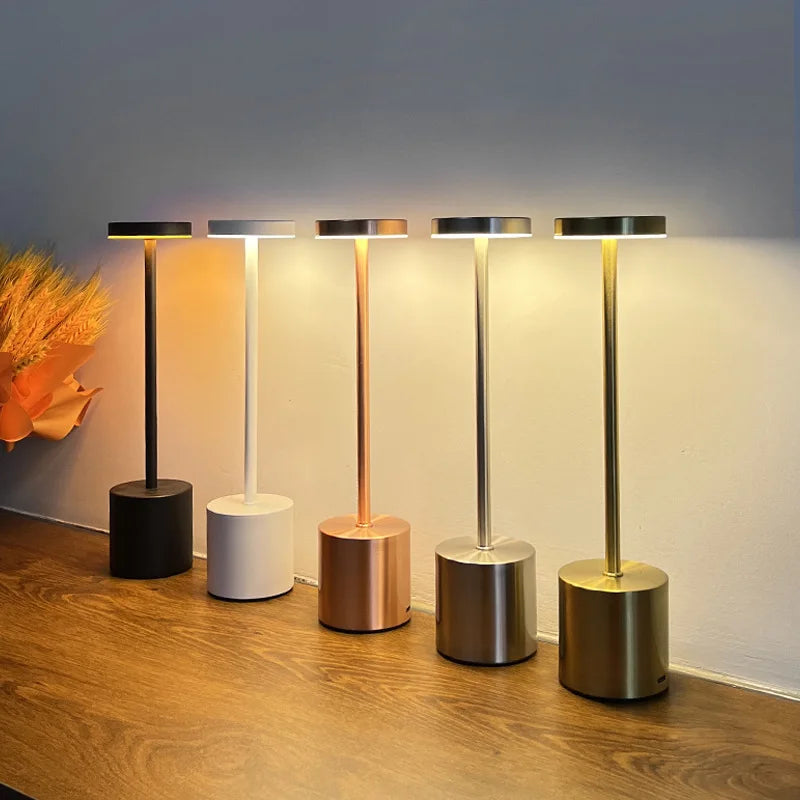 Five modern standing lamps with different base colors on a wooden floor.